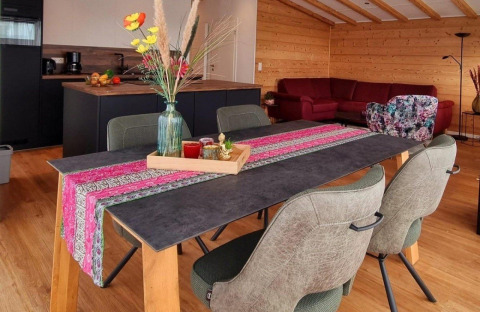 Eettafel met kleurrijke loper en vaas in moderne blokhut, Chalet Enzian, Camping & Ferienpark Brilon, Duitsland.