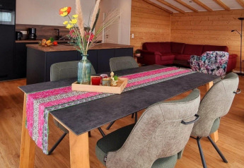 Tavolo da pranzo con runner colorato e vaso in chalet moderno, Chalet Enzian, Camping & Ferienpark Brilon, Germania.