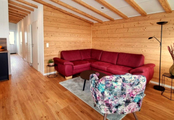 Woonkamer in Chalet Enzian, Camping & Ferienpark Brilon, met rode bank en houten wanden.