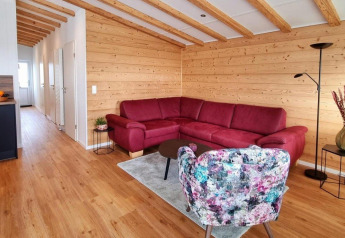 Living room in Chalet Enzian at Camping & Ferienpark Brilon with red sofa, wood walls and beams.