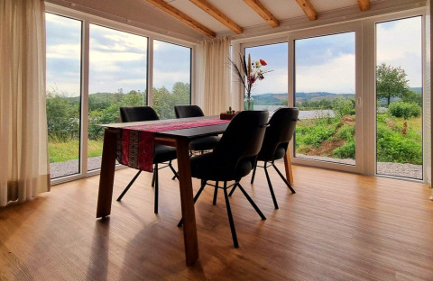 Dining area with black chairs and panoramic windows in Chalet Enzian at Camping & Ferienpark Brilon.