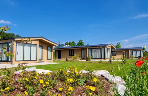 Chalet Enzian at Camping & Ferienpark Brilon, Germany, modern cabins with gardens and blue sky view.