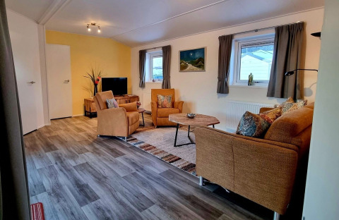 Woonkamer in Chalet Limonet bij Camping & Ferienpark Brilon met bruine banken en houten vloer.