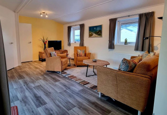 Living room in Chalet Limonet at Camping & Ferienpark Brilon, with brown sofas and wood flooring.