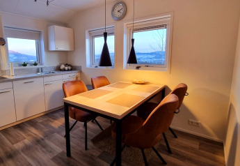 Modern dining area inside Chalet Limonet mobile home at Camping & Ferienpark Brilon, with brown chairs and kitchen.
