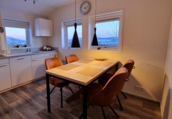 Modern dining area inside Chalet Limonet mobile home at Camping & Ferienpark Brilon, with brown chairs and kitchen.