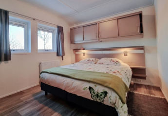 Bedroom of Chalet Limonet at Camping & Ferienpark Brilon, Germany, with double bed, windows, and cabinets.