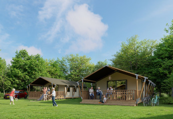 People relax and play near Avonturenlodge DeLuxe safari tents at Kampeerdorp de Zandstuve in the Netherlands.