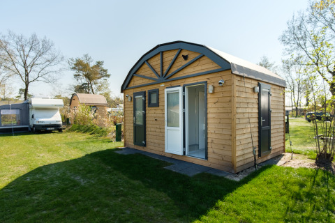 Safaritent De Waard Tunneltent met privé sanitair op Kampeerdorp de Zandstuve in Nederland, op een gazon.