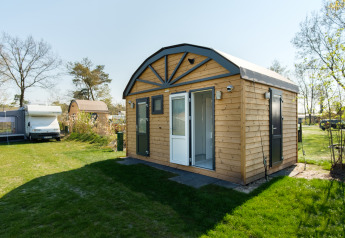 Moderne safari-telt med privat sanitær ved Kampeerdorp de Zandstuve i Holland, omgivet af grønt område.
