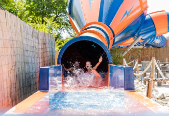 Dos niños disfrutan saliendo de un tobogán acuático en Kampeerdorp de Zandstuve, Países Bajos.