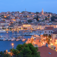 Panoramisch uitzicht op Mali Lošinj, Kroatië, bij schemering met jachthaven en verlichte huizen.