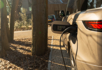 Coche eléctrico cargándose al aire libre en Suite at Woodz Lodges en Bélgica, rodeado de árboles.