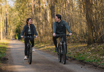 Dos personas montando bicicleta por un sendero de bosque cerca de Suite at Woodz Lodges en Bélgica.