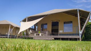 Tienda tipo safari Safari cottage con porche en Holiday park De Boshoek, Países Bajos, bajo cielo azul.