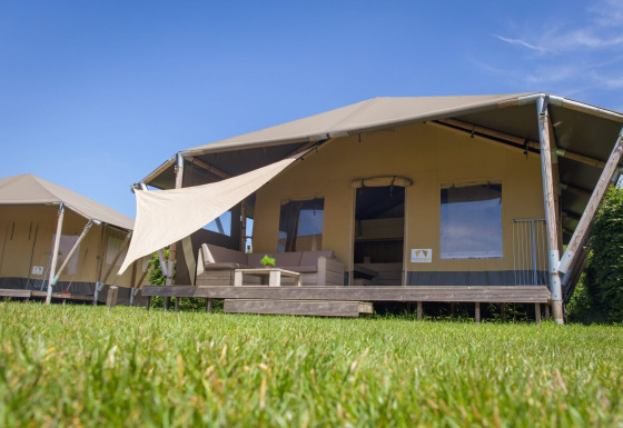 Tente safari Safari cottage avec terrasse au Holiday park De Boshoek, Pays-Bas, sous un ciel bleu.