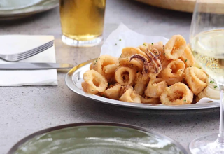 Een bord gefrituurde calamares, bier en wijn op tafel bij Wecamp Cádiz vakantiepark in Andalusië.