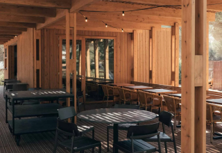 Terrazza in legno con tavoli e sedie al parco vacanze Wecamp Cádiz in Andalusia, Spagna.