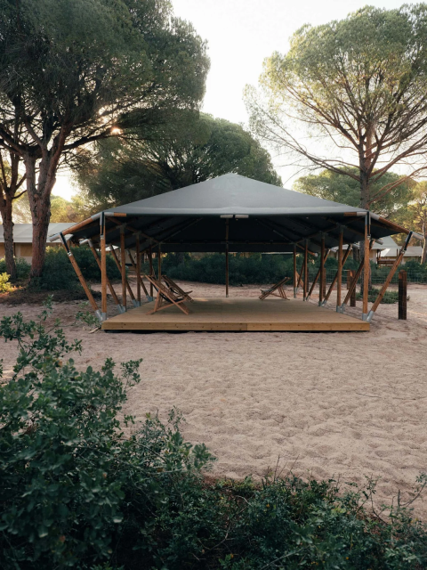 Tenda moderna con struttura in legno e sdraio a Wecamp Cádiz, circondata da pini in Andalusia, Spagna.