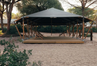 A modern wooden-framed tent with lounge chairs at Wecamp Cádiz, surrounded by pine trees in Andalusia, Spain.