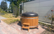 Houten hottub met zwart deksel en trapje naast een moderne lodge in Zuiderzee, Nederland.