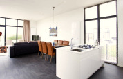 Espace salon et cuisine moderne et lumineux dans le lodge L-Cube au Zuiderzee, Pays-Bas, avec grandes fenêtres.