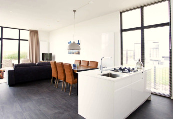 Espace salon et cuisine moderne et lumineux dans le lodge L-Cube au Zuiderzee, Pays-Bas, avec grandes fenêtres.