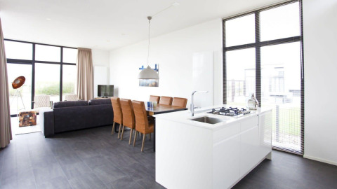 Heldere, moderne leefruimte en keuken in de L-Cube lodge bij Zuiderzee, Nederland, met grote ramen en stijl.