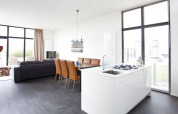 Heldere, moderne leefruimte en keuken in de L-Cube lodge bij Zuiderzee, Nederland, met grote ramen en stijl.
