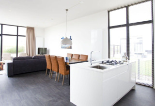Heldere, moderne leefruimte en keuken in de L-Cube lodge bij Zuiderzee, Nederland, met grote ramen en stijl.