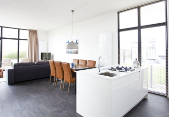 Heldere, moderne leefruimte en keuken in de L-Cube lodge bij Zuiderzee, Nederland, met grote ramen en stijl.