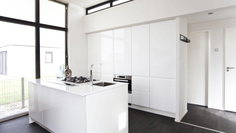 Minimalistische, moderne keuken in L-Cube lodge aan de Zuiderzee, Nederland, met witte kasten en grote ramen.