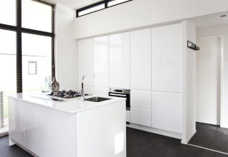 Minimalistische, moderne keuken in L-Cube lodge aan de Zuiderzee, Nederland, met witte kasten en grote ramen.