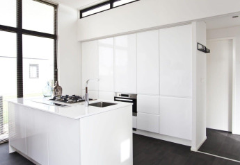 Minimalistische, moderne keuken in L-Cube lodge aan de Zuiderzee, Nederland, met witte kasten en grote ramen.