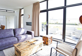 Heldere, moderne woonkamer met grote ramen in de L-Cube lodge aan de Zuiderzee, Nederland, zicht op terras.