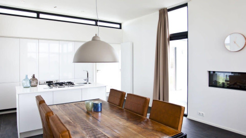 Moderne eetruimte en keuken in L-Cube-lodge aan de Zuiderzee, Nederland, met bruine stoelen.