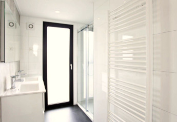 Salle de bain moderne au lodge L-Cube à Zuiderzee, Pays-Bas, avec douche en verre et grande porte.