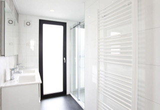 Modern badkamer in het L-Cube lodge aan de Zuiderzee in Nederland met glazen douche en grote deur.