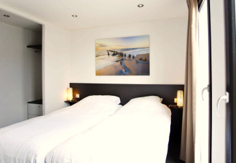 Chambre lumineuse et moderne à L-Cube lodge, Zuiderzee, Pays-Bas, avec grandes fenêtres et décoration élégante.