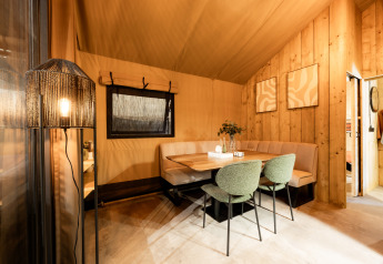 Coin repas dans une tente safari de luxe, boiseries et mobilier moderne à Kampeerdorp de Zandstuve.