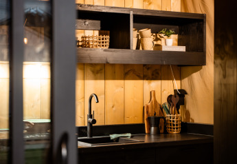 Cocina moderna en una tienda safari con paredes de madera, estanterías abiertas y grifería negra.