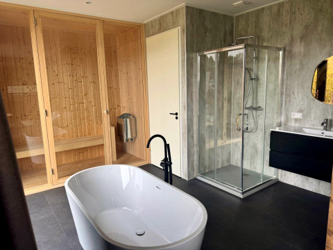 Moderne badeværelse på Modus Wellness 2 lodge med fritstående badekar, sauna, bruser og håndvask.