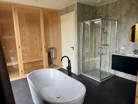 Modernes Badezimmer in der Modus Wellness 2 Lodge mit freistehender Badewanne, Sauna und Duschkabine.