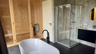 Modernes Badezimmer in der Modus Wellness 2 Lodge mit freistehender Badewanne, Sauna und Duschkabine.