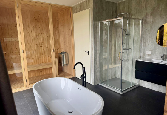Modernes Badezimmer in der Modus Wellness 2 Lodge mit freistehender Badewanne, Sauna und Duschkabine.