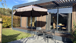 Terrasse extérieure du lodge Modus Wellness 2 à Zuiderzee, Pays-Bas, avec table, chaises et grand parasol.
