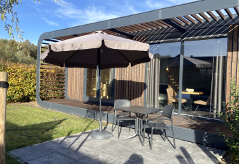 Terrasse am Modus Wellness 2 Lodge in Zuiderzee, Niederlande, mit Tisch, Stühlen und Sonnenschirm.