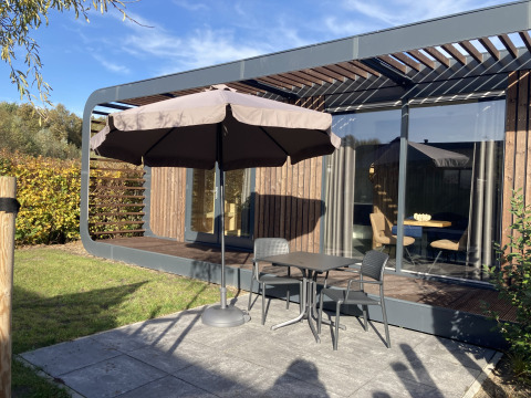 Terrasse am Modus Wellness 2 Lodge in Zuiderzee, Niederlande, mit Tisch, Stühlen und Sonnenschirm.
