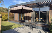 Terrasse am Modus Wellness 2 Lodge in Zuiderzee, Niederlande, mit Tisch, Stühlen und Sonnenschirm.