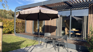 Outdoor terrace at Modus Wellness 2 lodge in Zuiderzee, Netherlands, with table, chairs and a large umbrella.